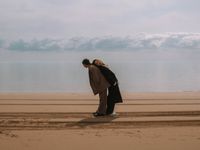 Zwei Personen am Strand die Rücken an Rücken stehen